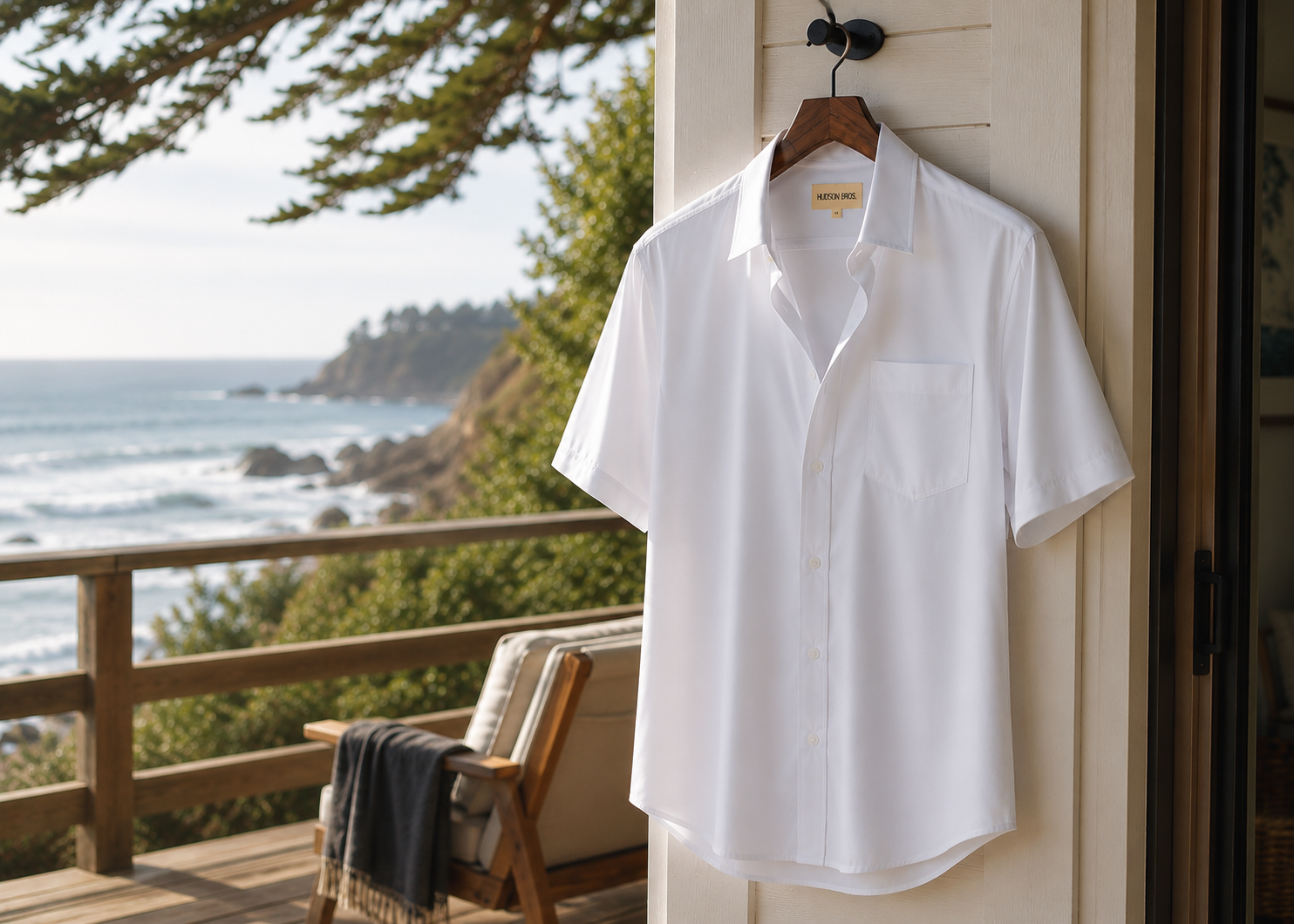 White short sleeve button up shirt hanging on a coastal porch overlooking the ocean